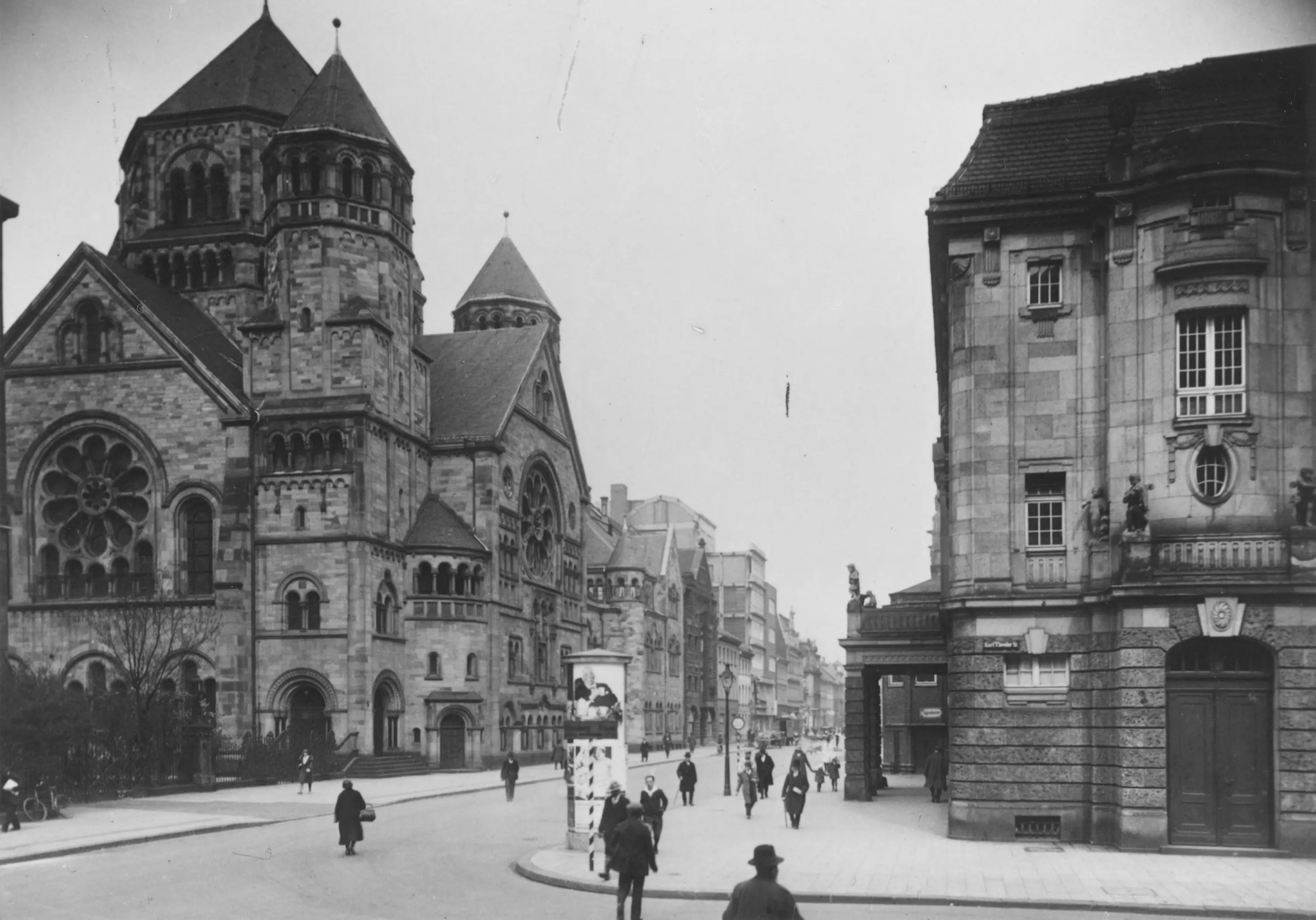 Historische Straßenansicht mit einer großen Synagoge im romanischen Stil und umliegenden Gebäuden.